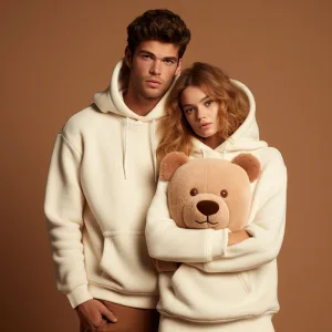 Two models in matching beige hoodies with teddy bear.