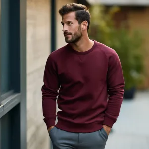 Man in stylish maroon sweater looking away outdoors.