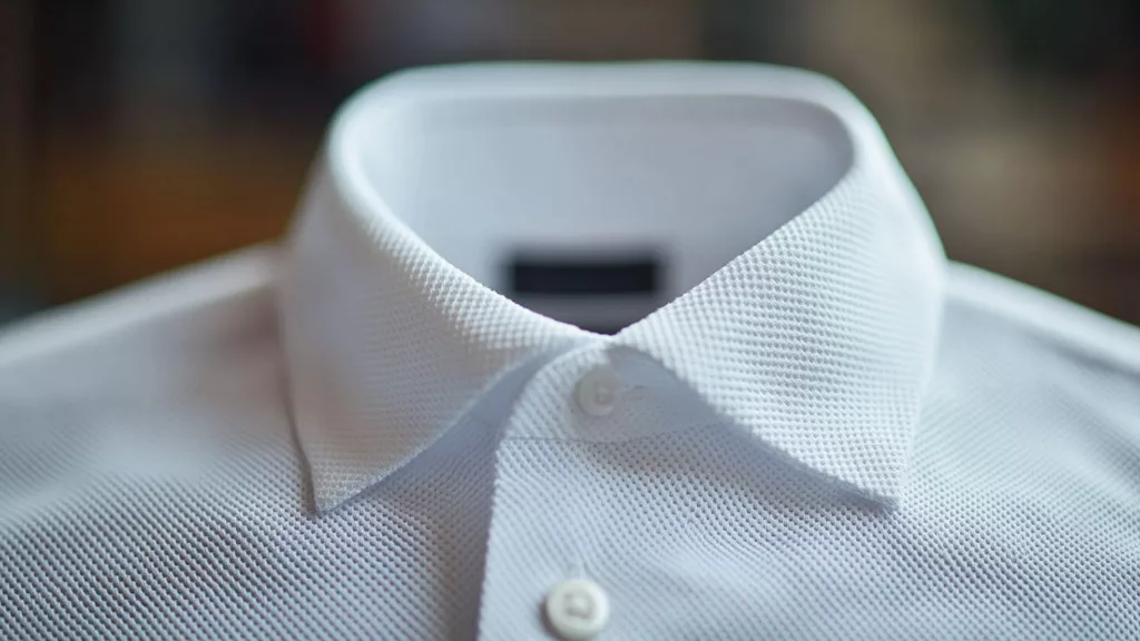 Close up of the textured fabric of a white polo shirt emphasizing its softness and premium quality b Close-up of the textured fabric of a white polo shirt, emphasizing its softness and premium quality