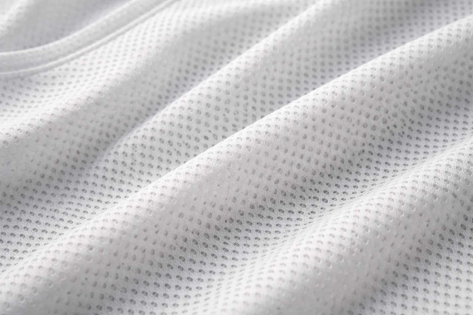A technical close-up image showing mesh fabric used in athletic apparel. The open weave is highlighted under soft lighting, emphasizing its breathability.